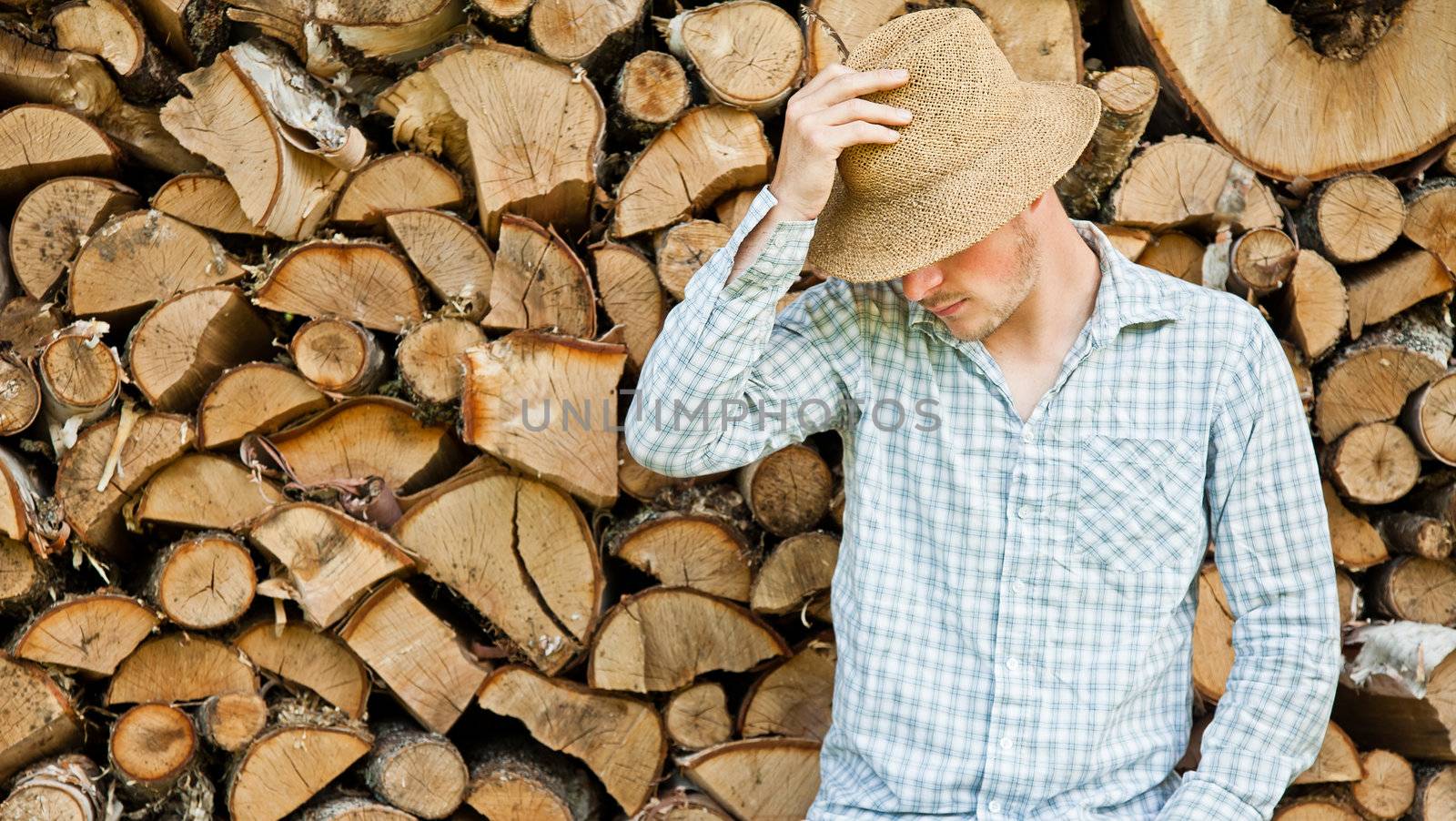 Woodcutter with straw hat on a background of wood