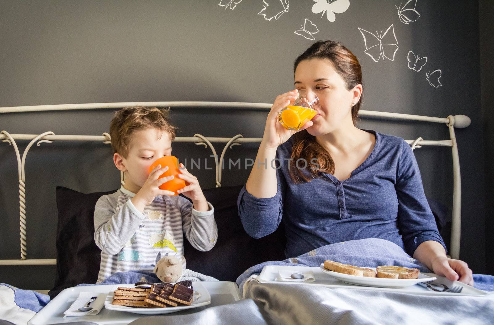 Mother and son having breakfast in bed by doble.d