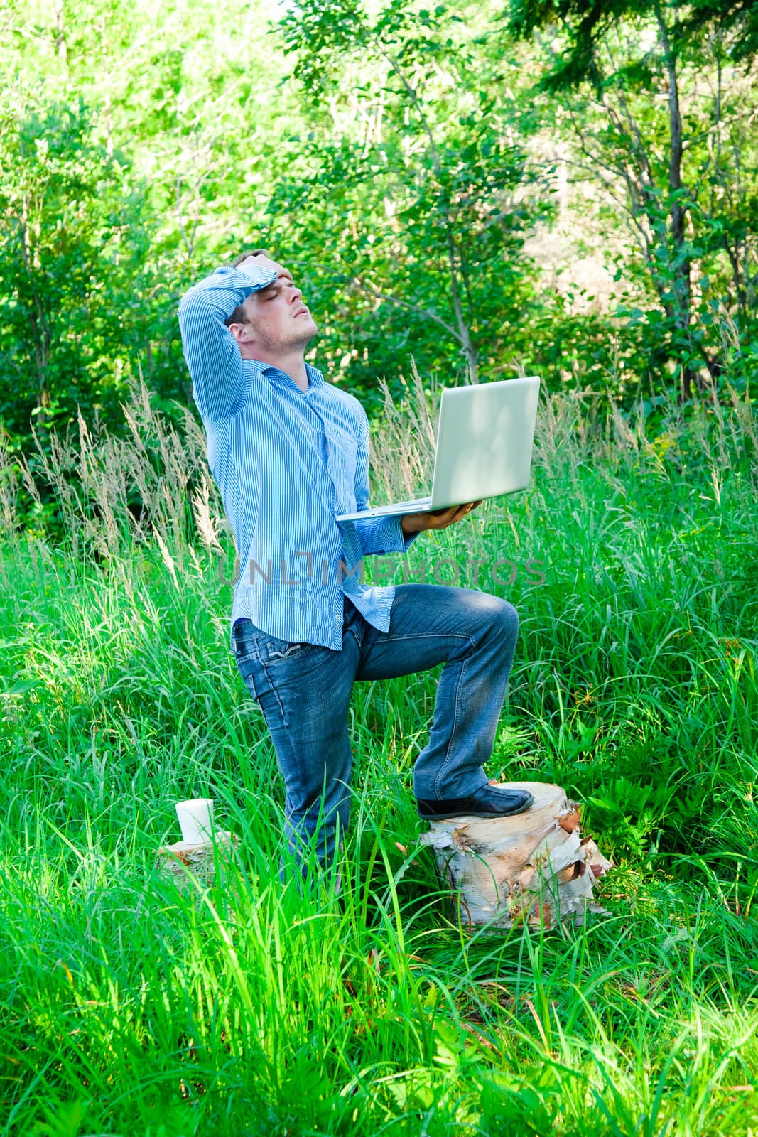 Despaired Young man outdoors with a cup and laptop