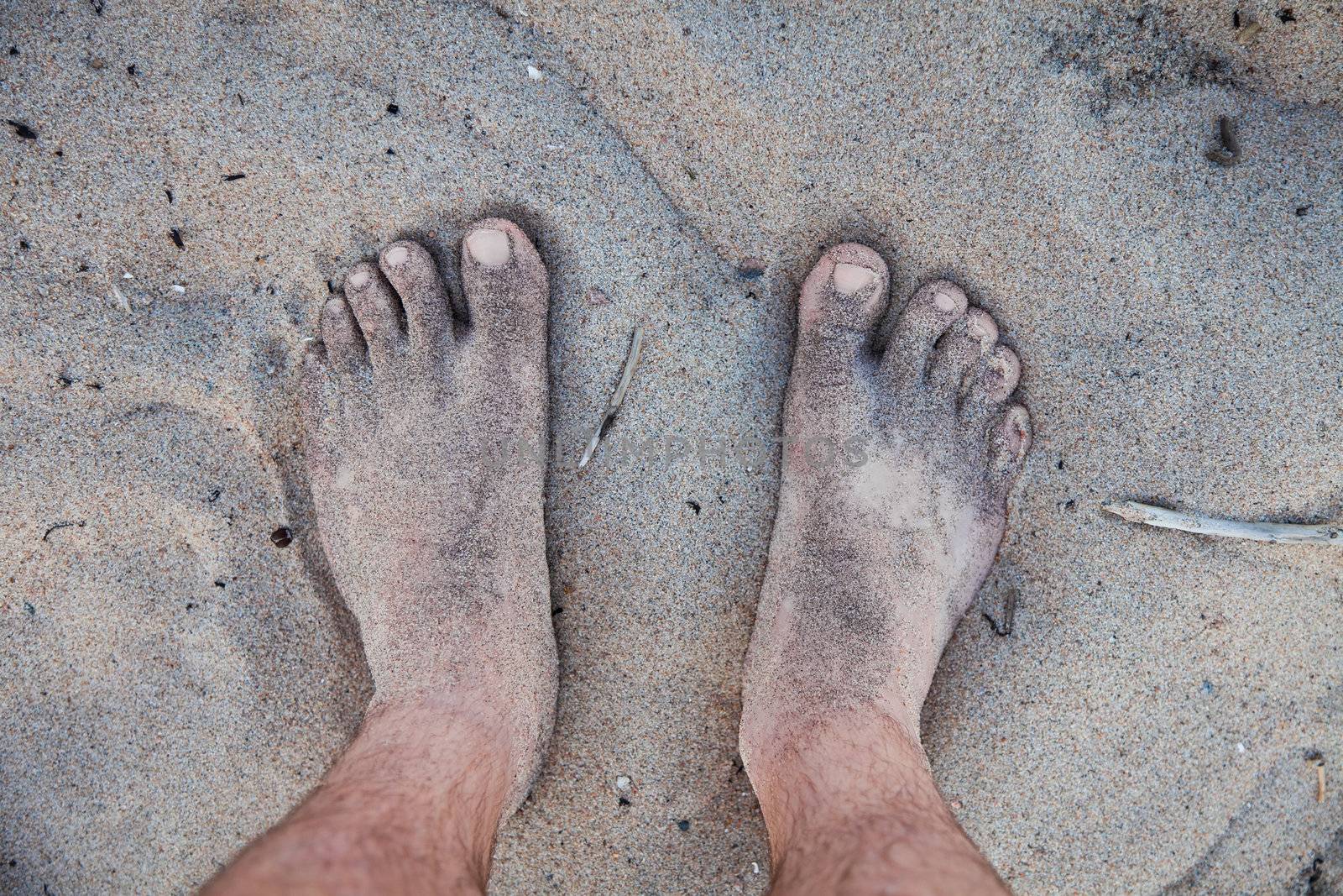 Men's barefoot feet in the sand