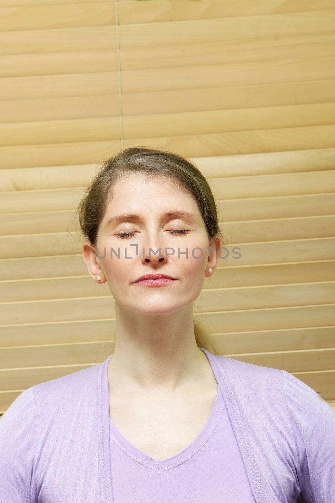 Head and shoulders portrait of an attractive middle-aged woman meditating with her eyes closed