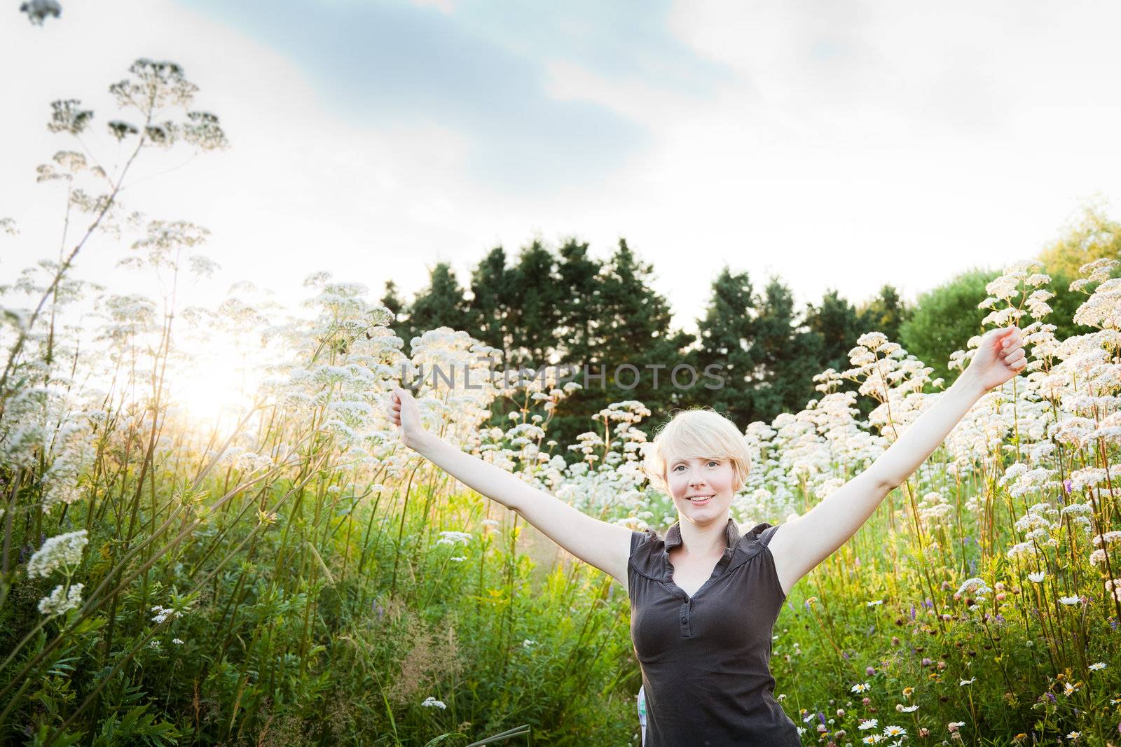 Girl in a field of flowers with arms in the air