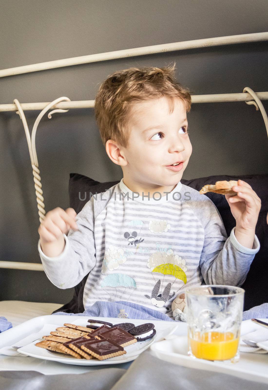 Happy child having breakfast in bed at home in the morning