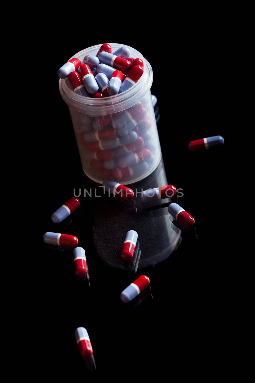 Container full of pills isolated on black background