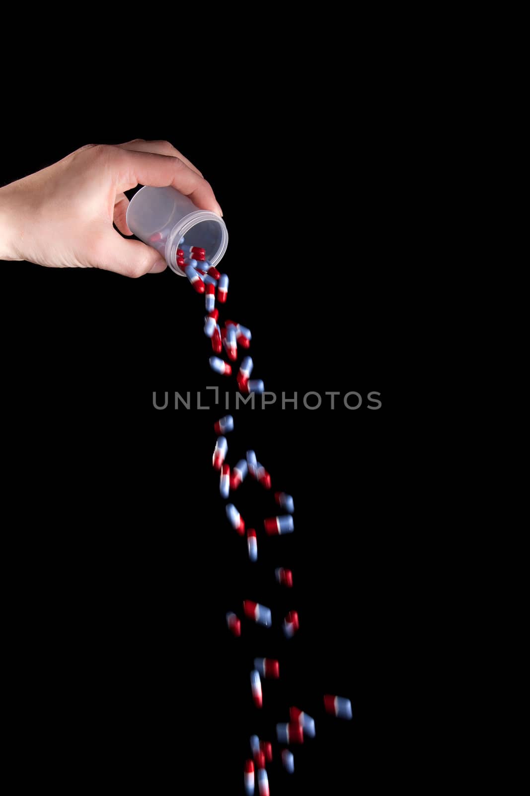 Empty a full container of capsules - isolated on black background