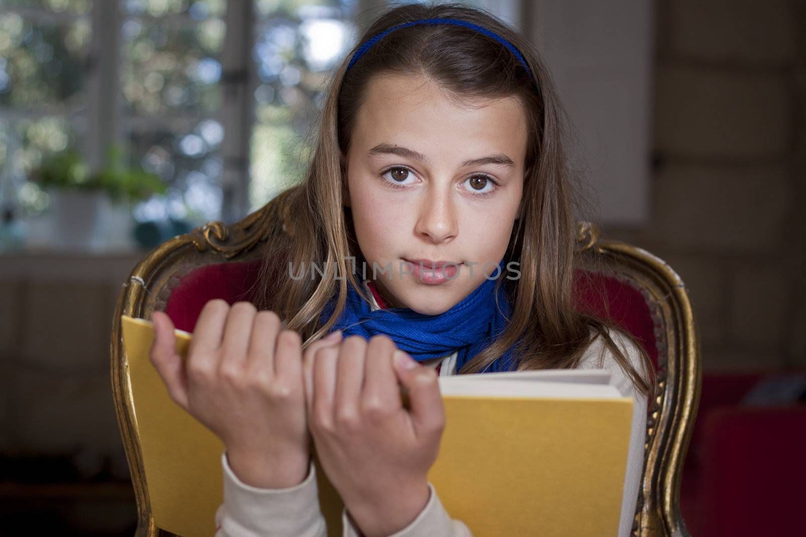 A young girl holding up a book, looking at camera, Real people, candid shot