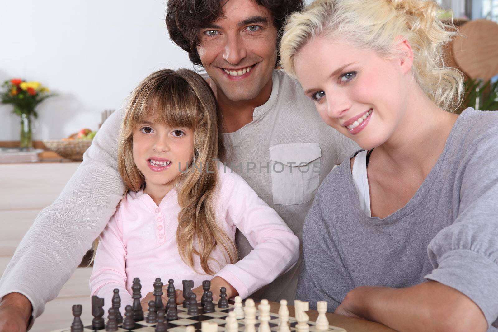 Family playing chess together by phovoir