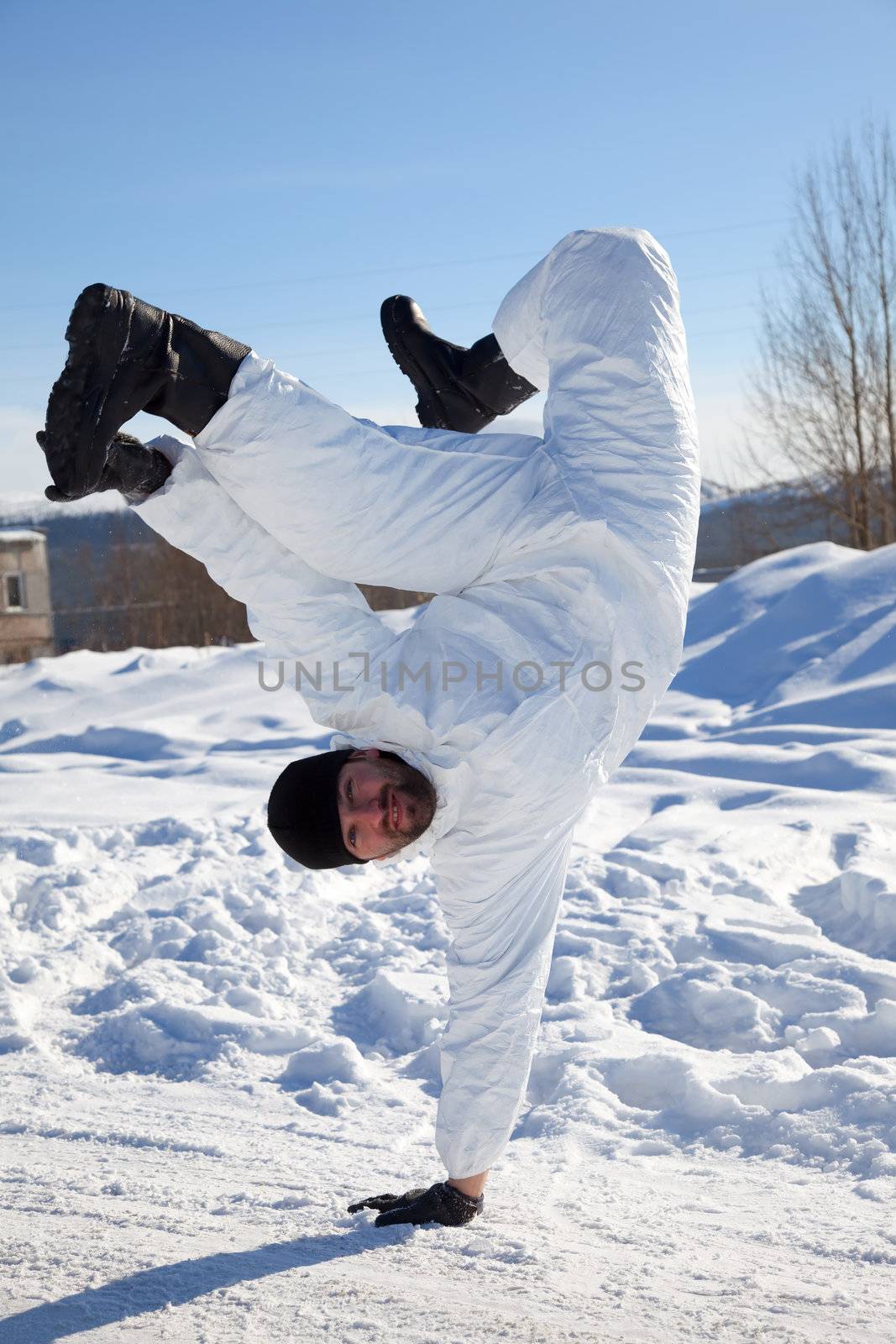 Soldier in white camouflage makes a break dance on the white snow