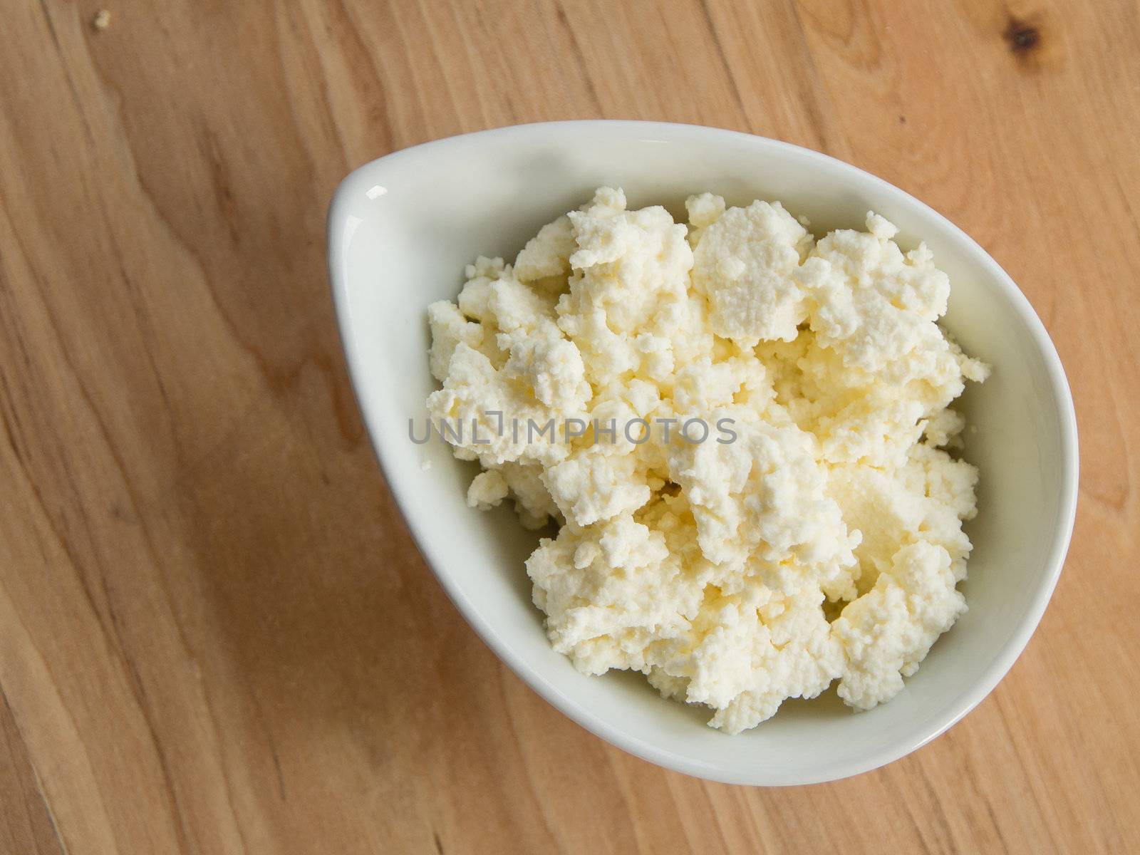 Homemade cottage cheese in a bowl on a cutting board