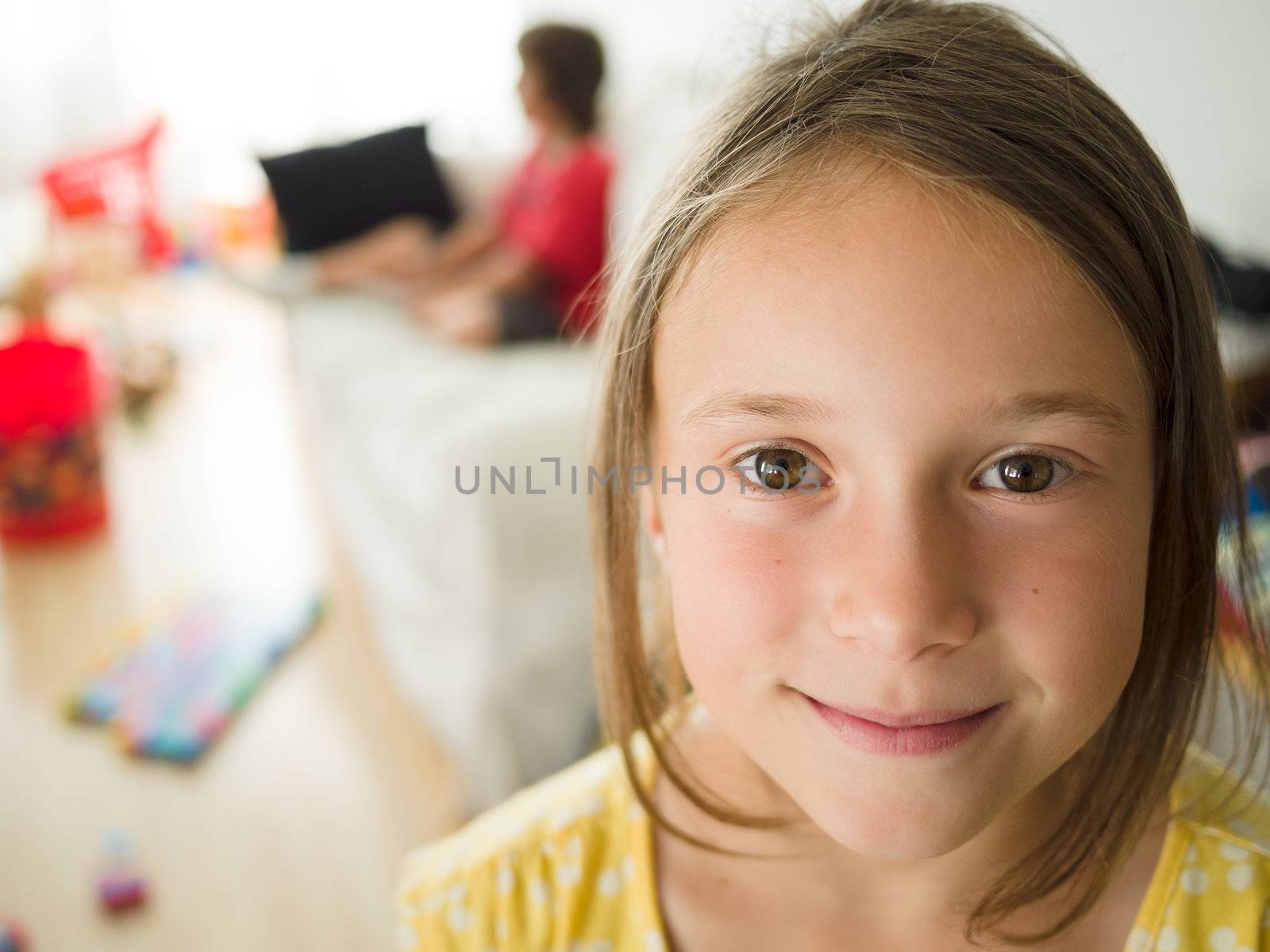 Little girl in a messy living room smiling