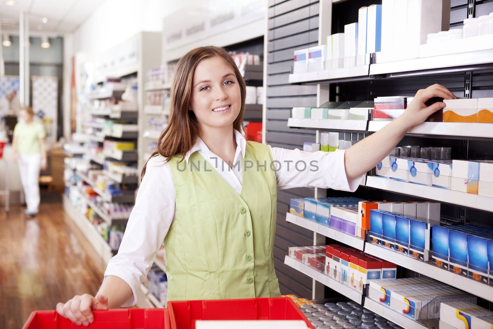 Young femail pharmacist looking for medicine in drugstore