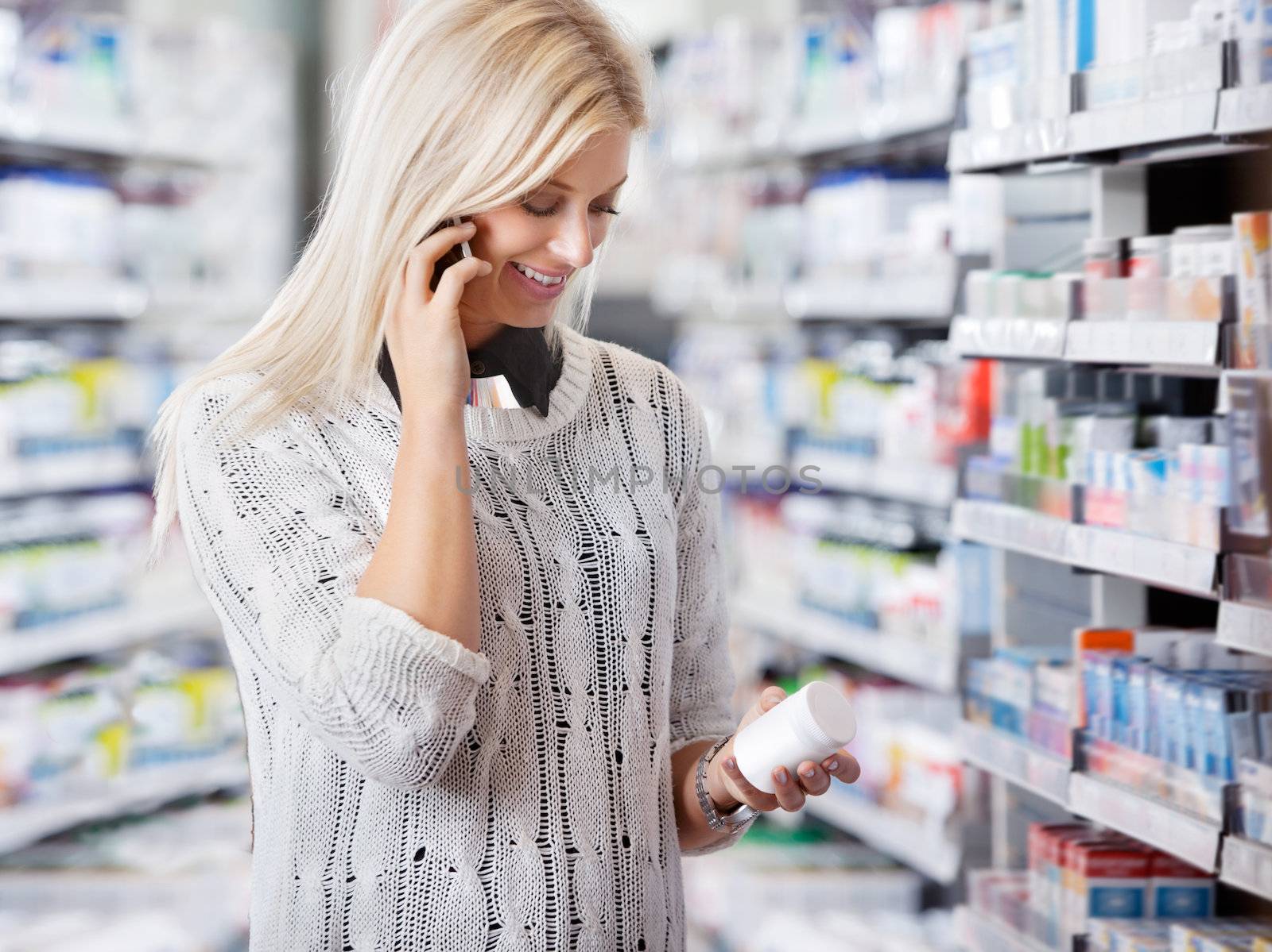 Woman holding medication container while talking on cell phone