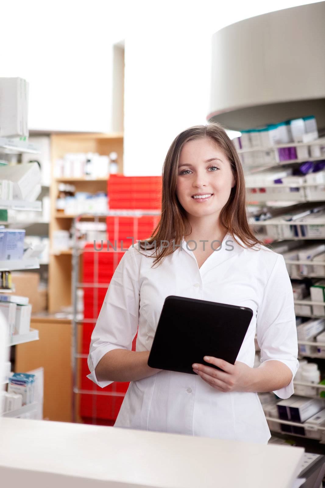 Portrait Of Smiling Female Pharmacist Holding Tablet Pc In Drugstore.