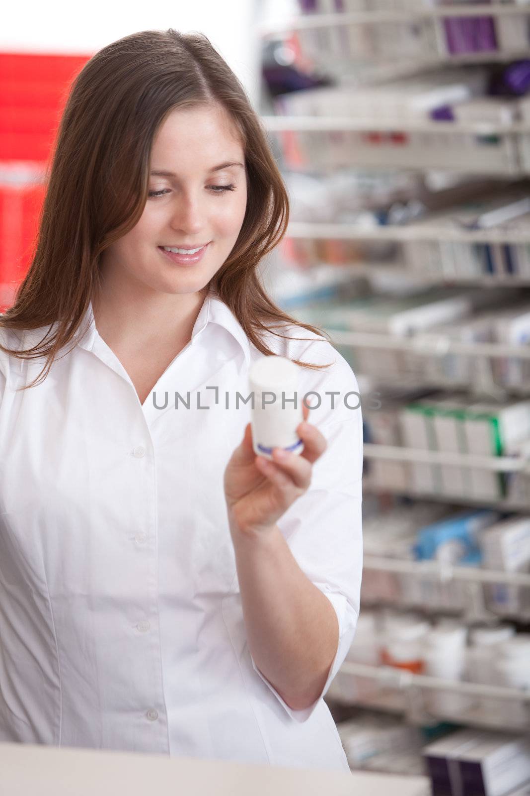Female Pharmacist Reading Information On Medicine by leaf