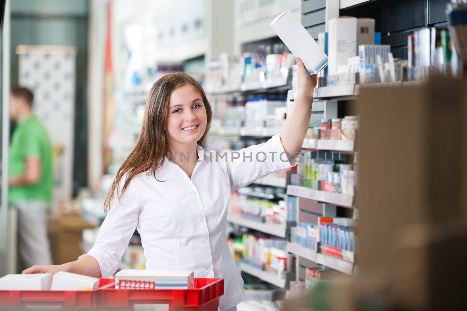 Portrait of female pharmacist keeping a box on shelf
