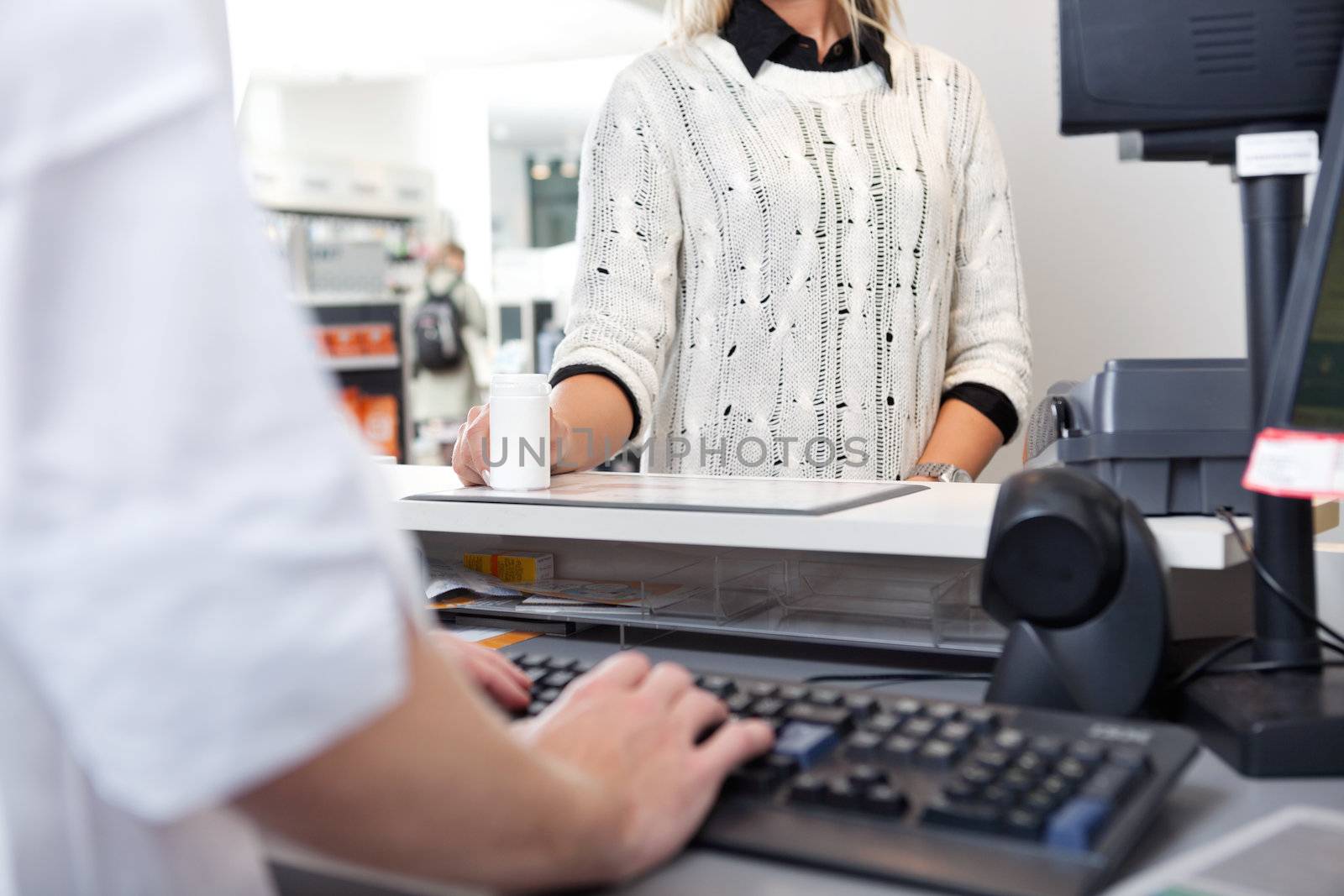 Mid-section of customer standing at checkout counter in drugstore