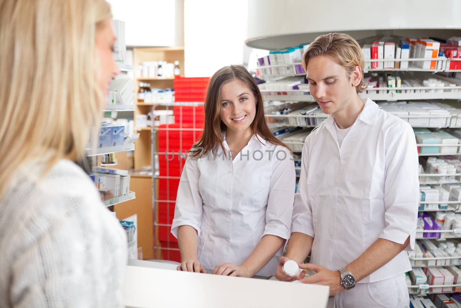 Two pharmacists standing at counter attending the customer