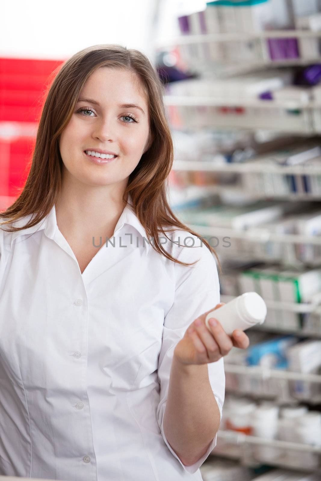 Portrait of female pharmacist holding medication container