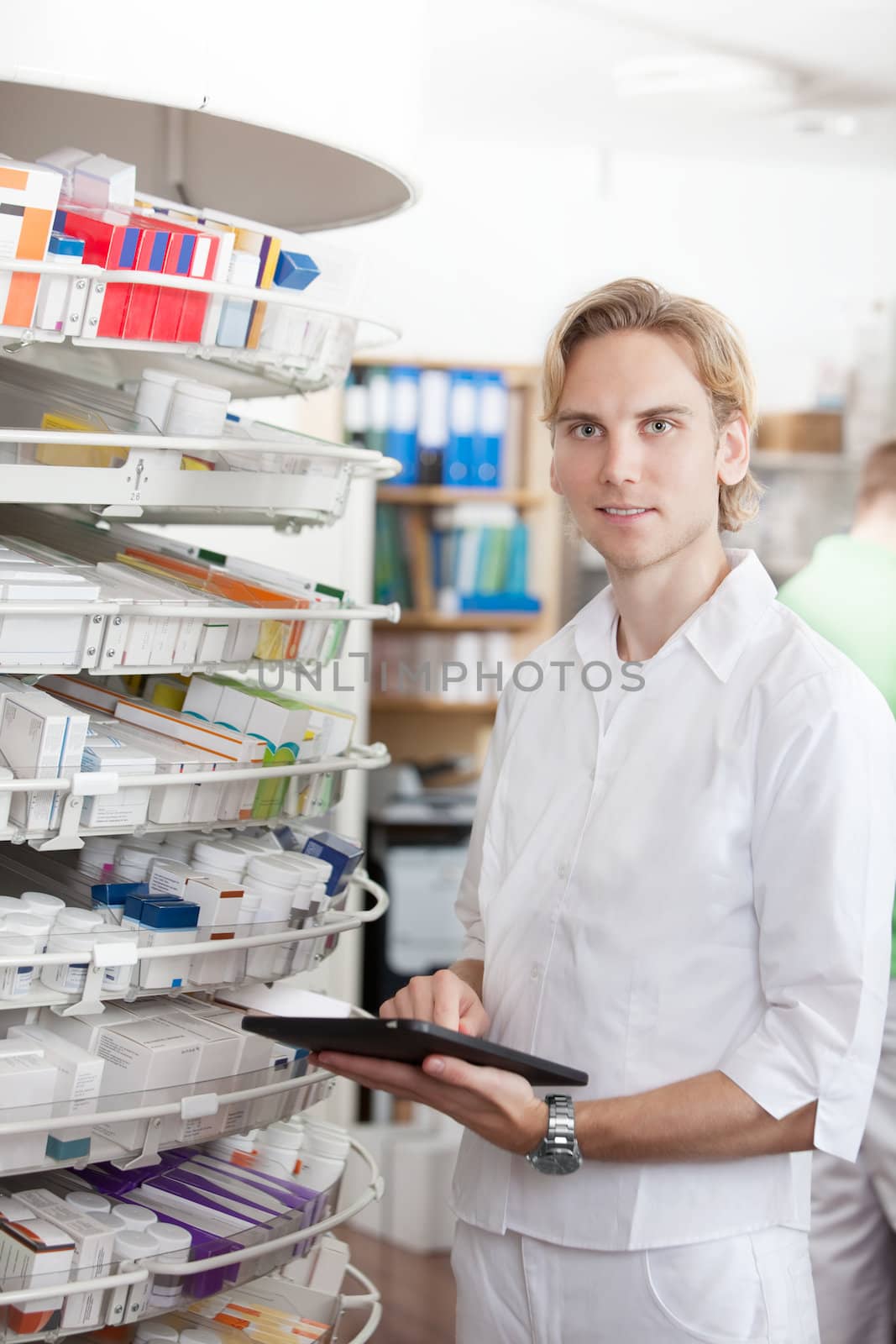 Portrait Of Smiling Male Pharmacist Holding Tablet Pc In Drugstore.