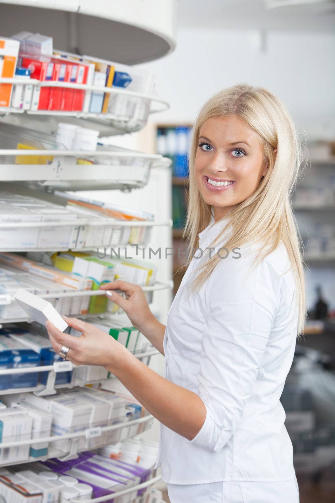 Portrait of woman standing in pharmacy drugstore holding medication box