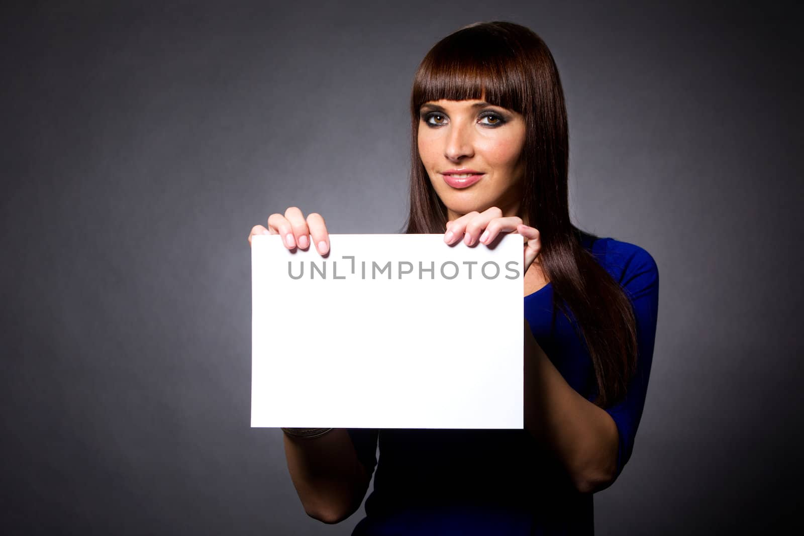 Happy attractive model holding white sign in studio