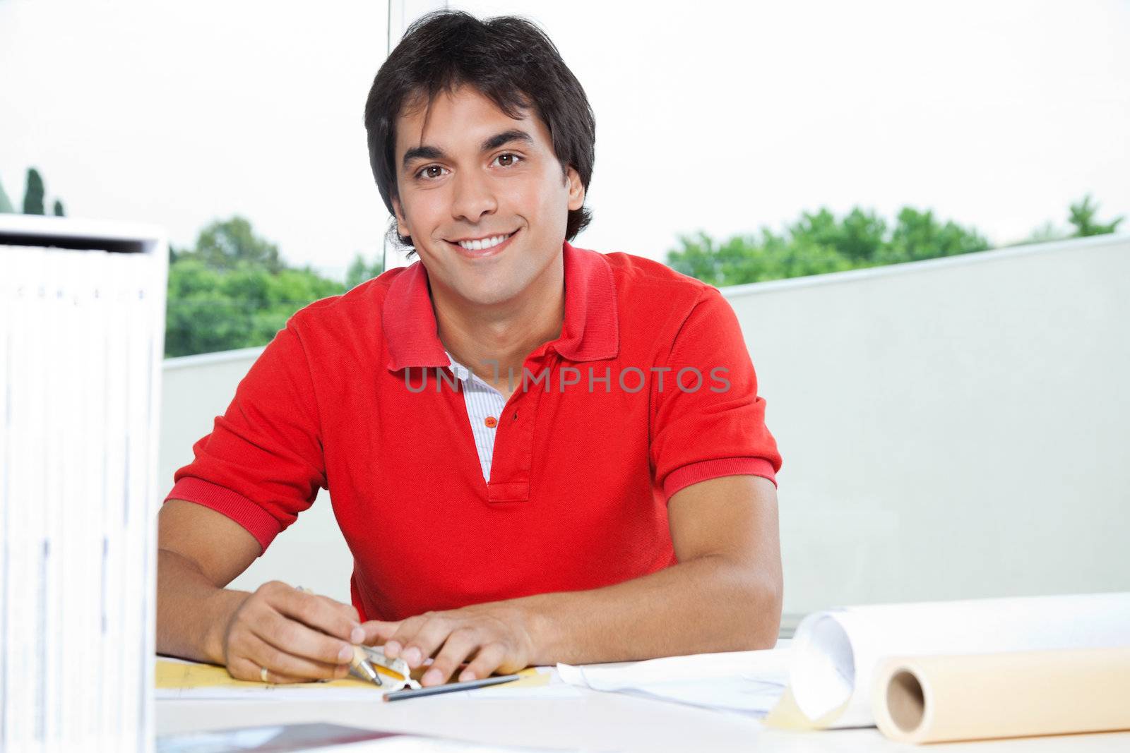 Portrait of young male architect smiling while working on a blueprint