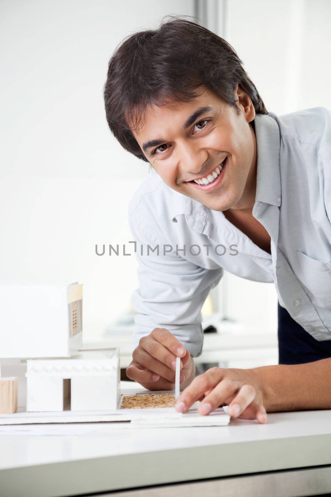 Portrait of young male architect smiling while creating a model house