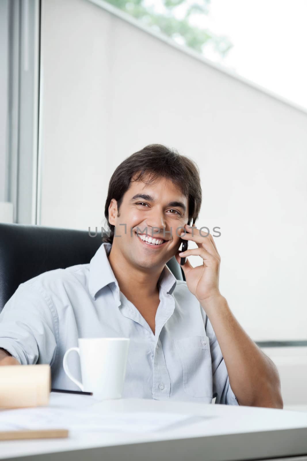 Portrait of happy male architect attending a phone call