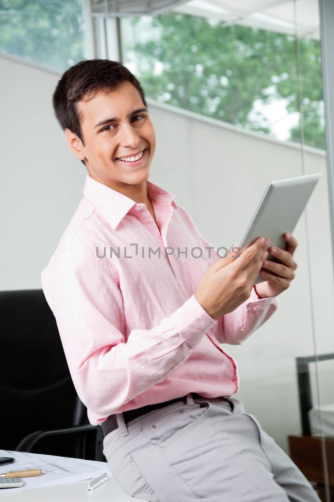 Portrait of happy young male business executive holding digital tablet