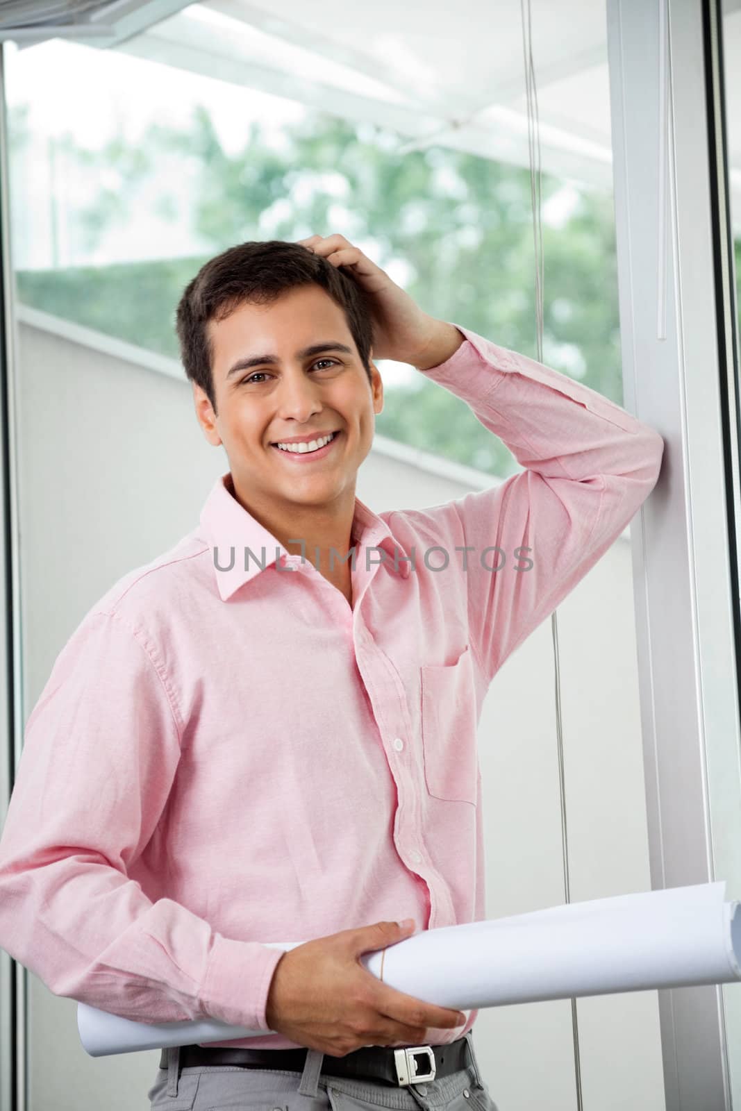 Portrait of young male architect smiling while holding a rolled up blueprint