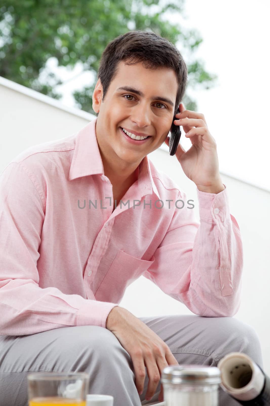 Portrait of male executive smiling while attending phone call