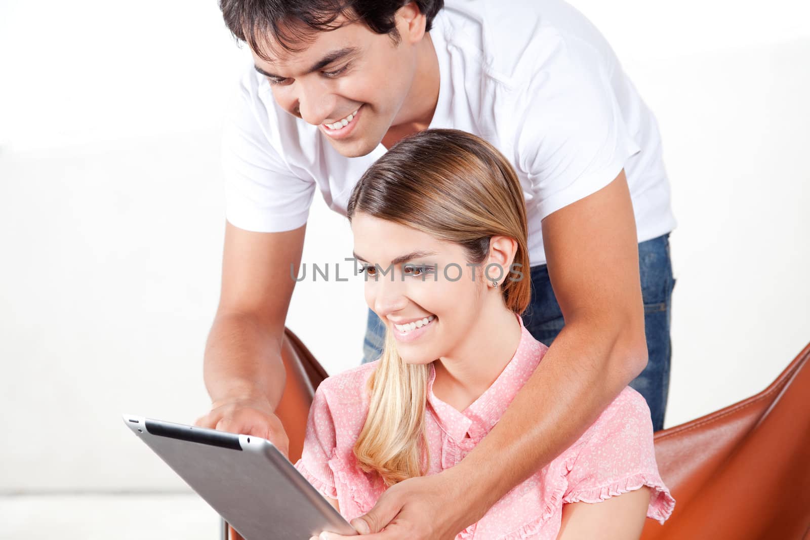 Happy young couple using digital tablet.