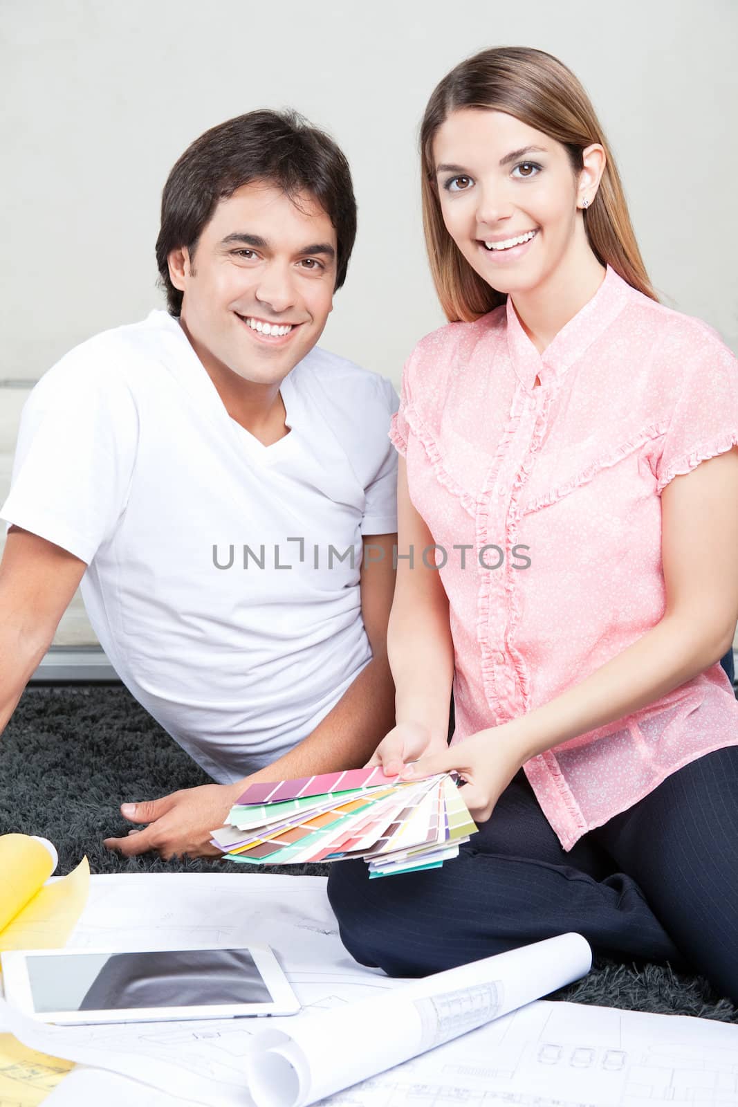 Happy Young Couple with Blueprints and Color Swatches by leaf