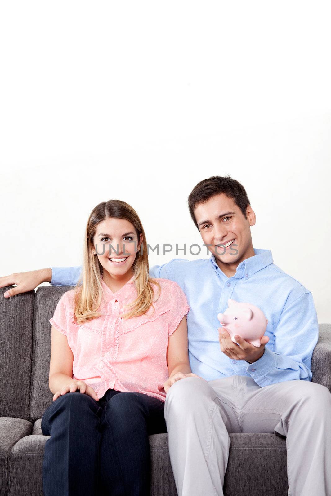 Young couple with a piggy bank sitting on couch