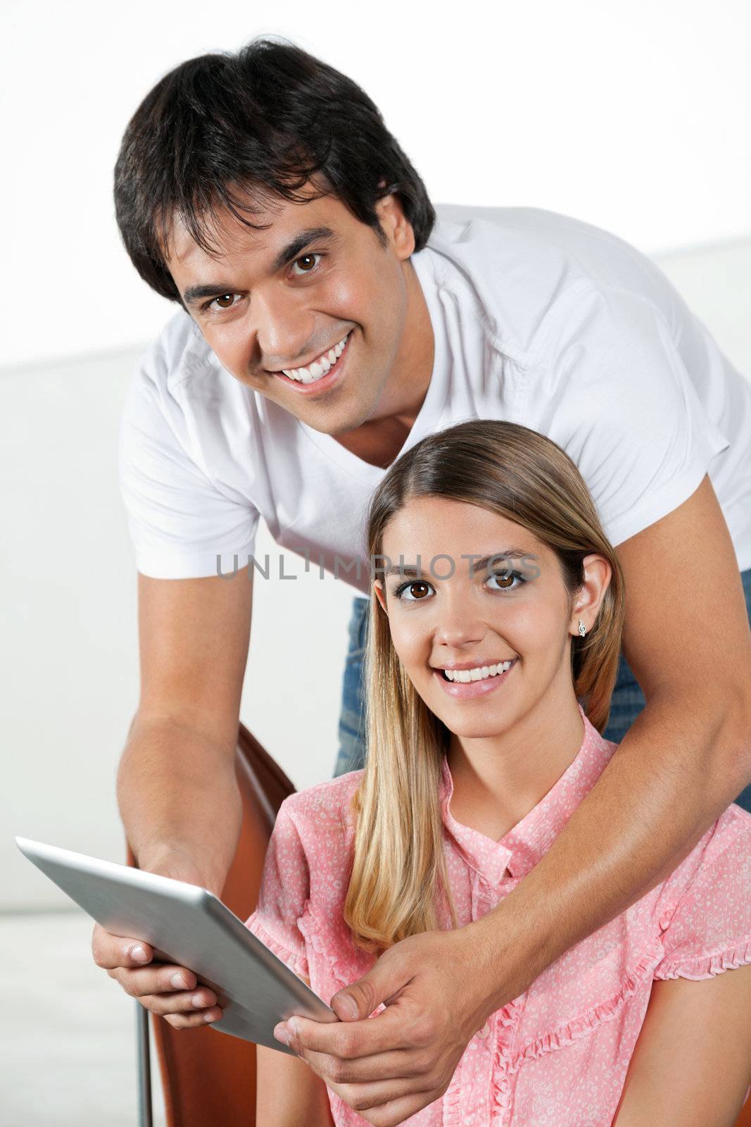 Portrait of happy young man with tablet PC standing behind woman