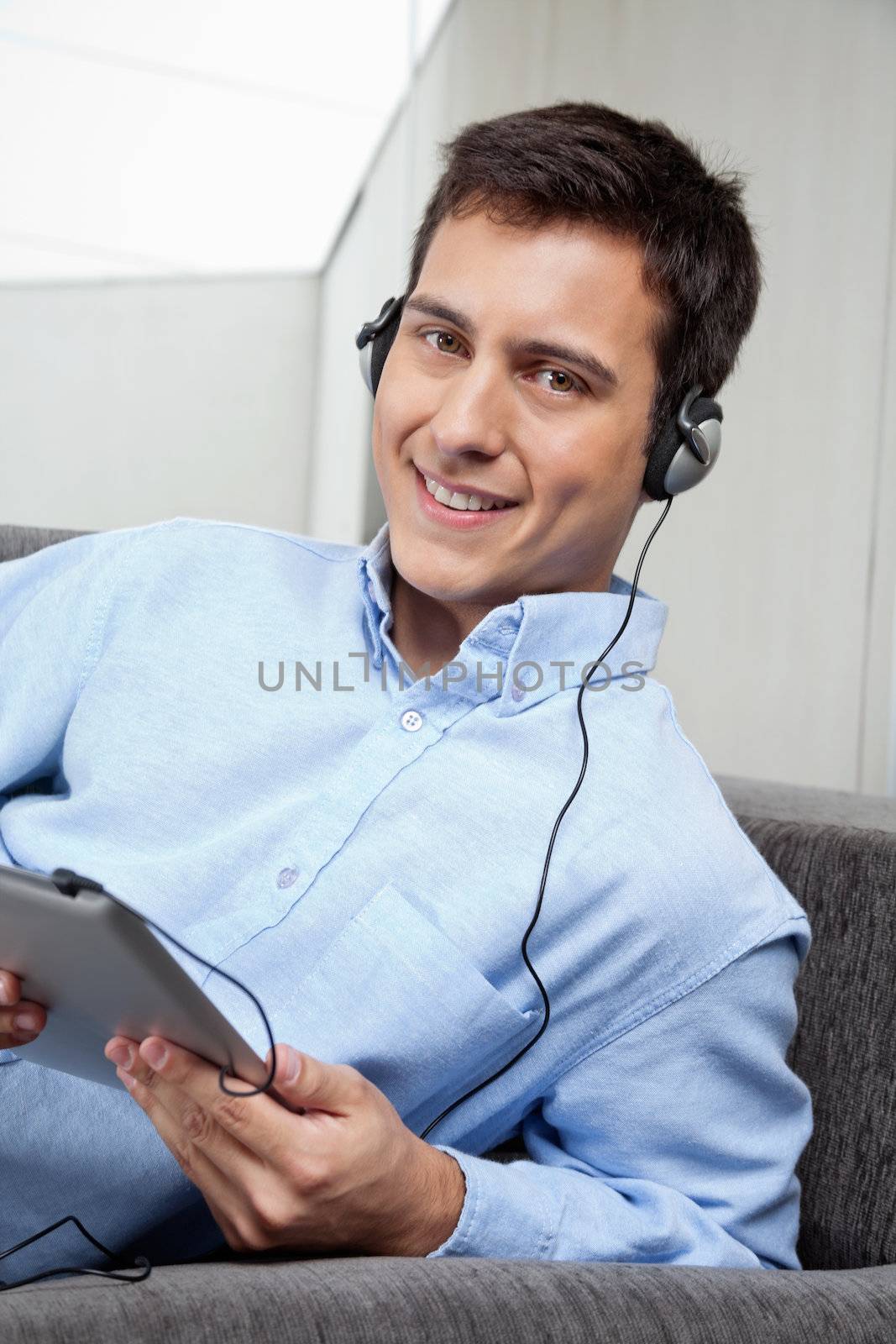 Young Man Listening Music On Digital Tablet by leaf