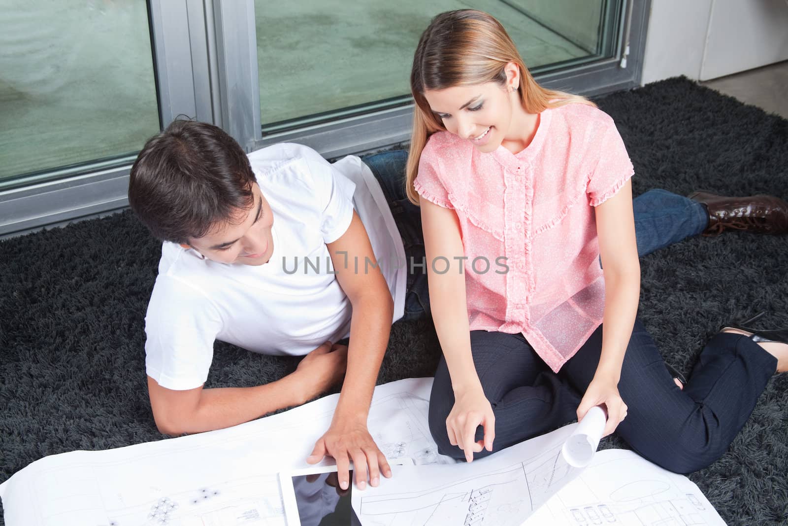 Young couple using digital tablet with blueprints .
