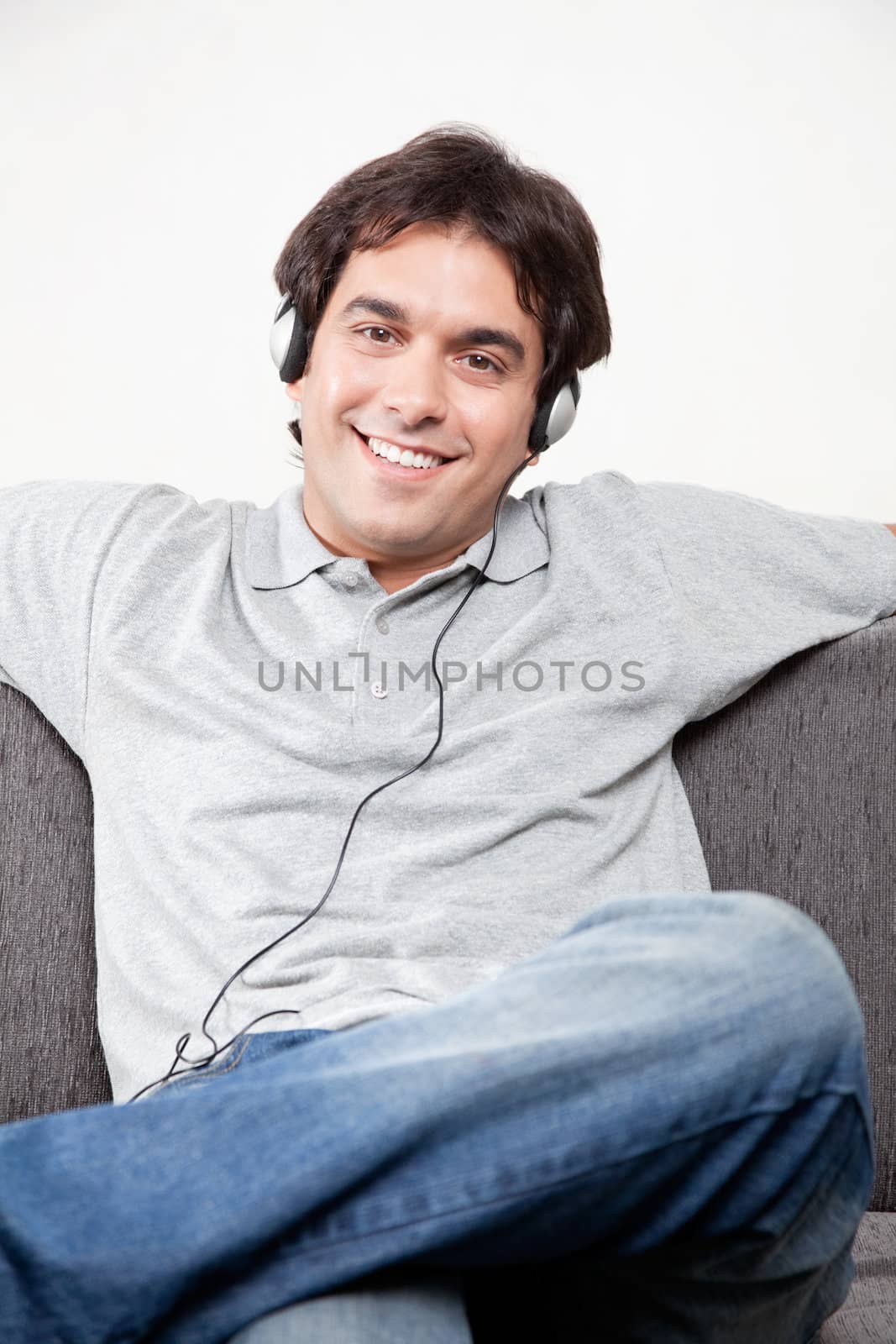 Relaxed young man on couch listening music.