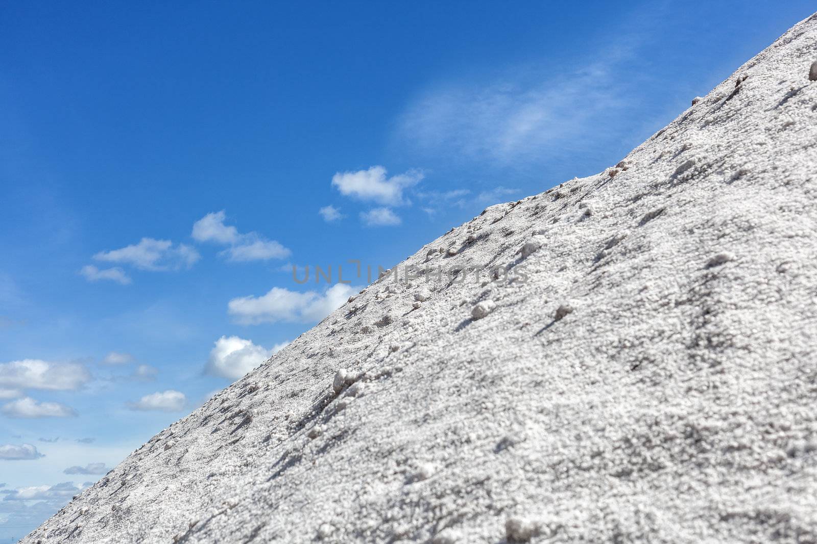 Big pile of freshly mined salt, set against a blue sky