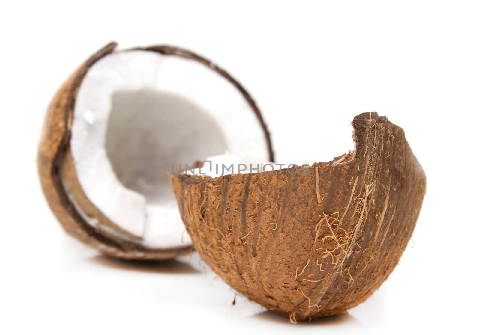 Closeup of cracked coconut on white background with light shadow. Shallow focus depth on front coconut 