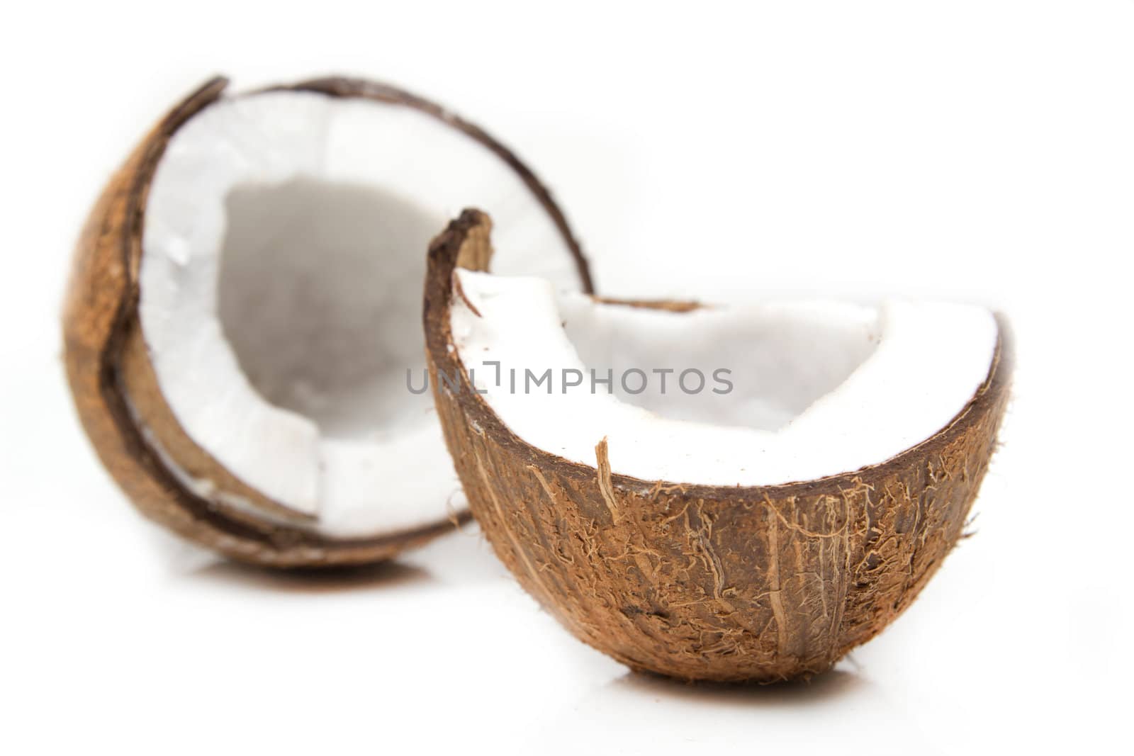 Closeup of cracked coconut on white background with light shadow. Shallow focus depth on front coconut 