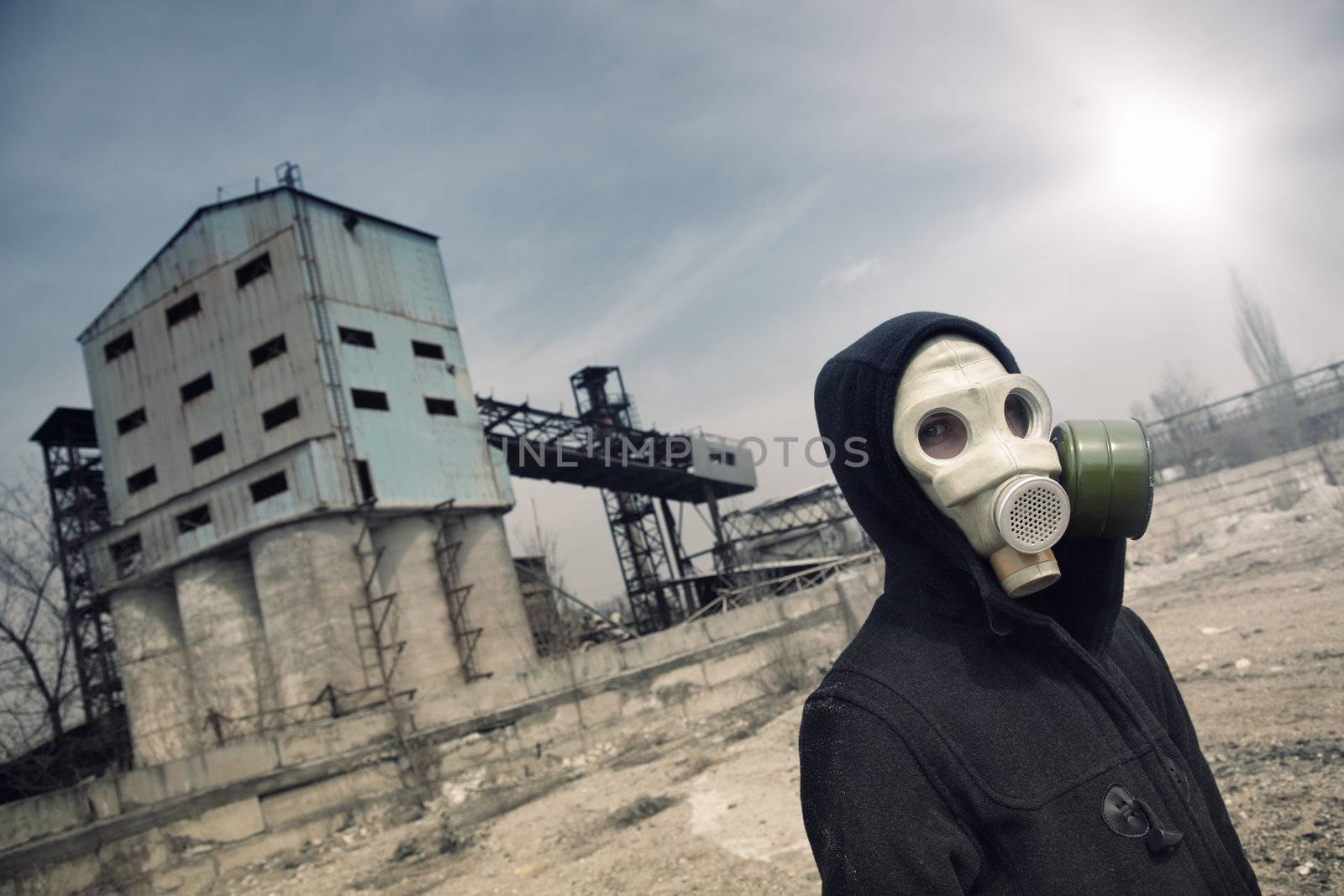 Human in gas mask outdoors and industrial factory on a background