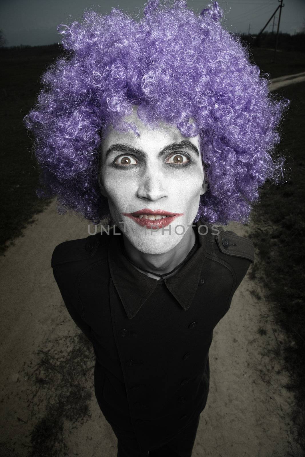 Crazy man outdoors with wig and clown makeup. Artistic darkness and colors added