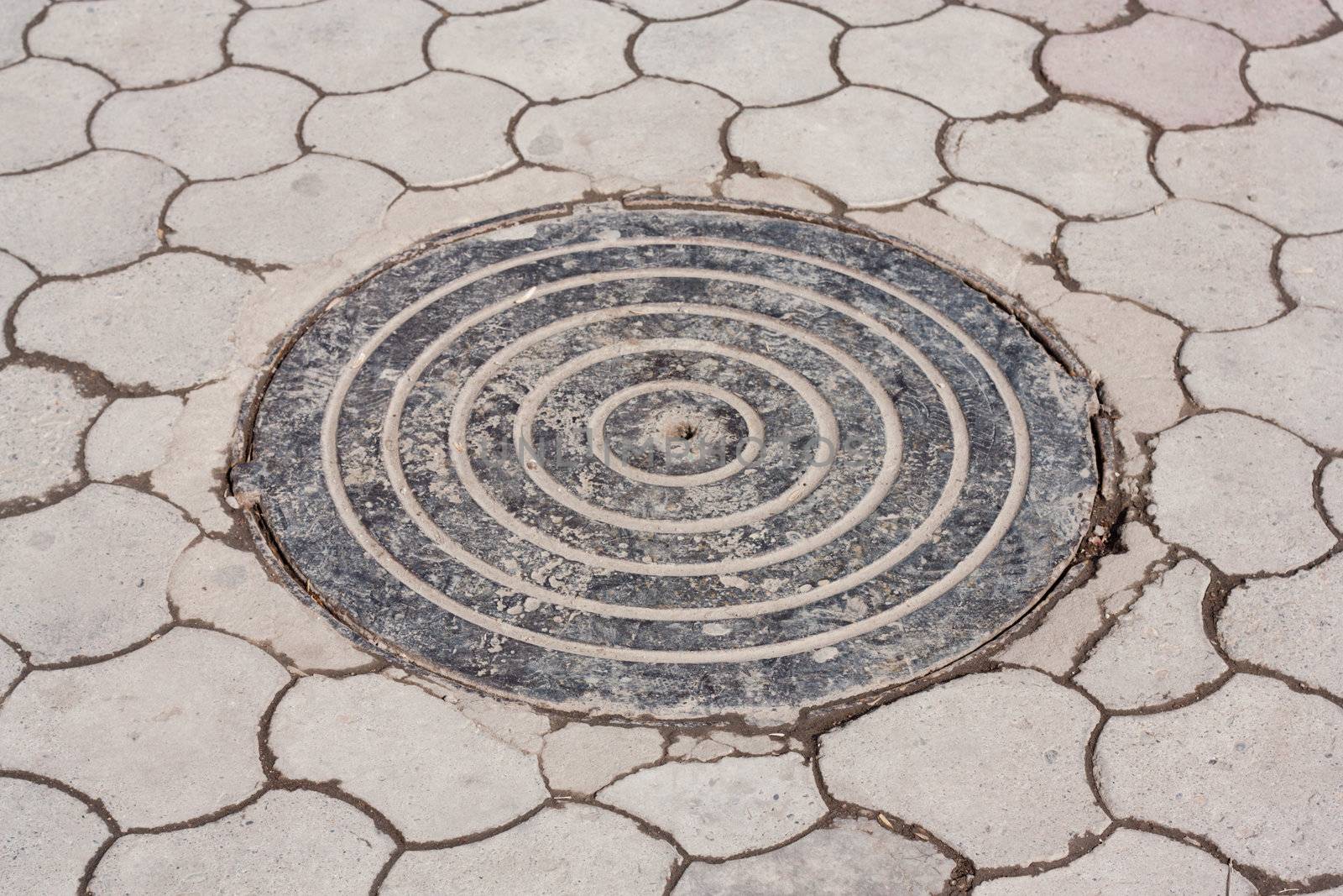 Cast iron manhole cover is inset into old brick street paving  by schankz