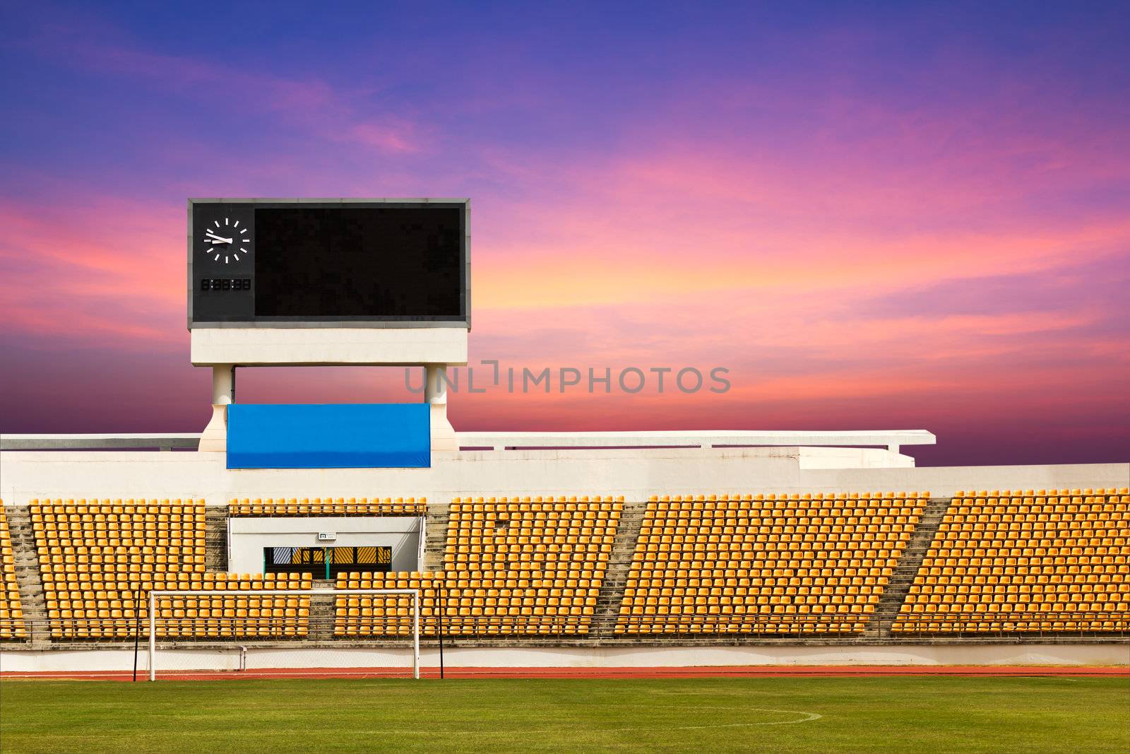 Rows of orange seats on the stadium with scoreboard displaying clock above them