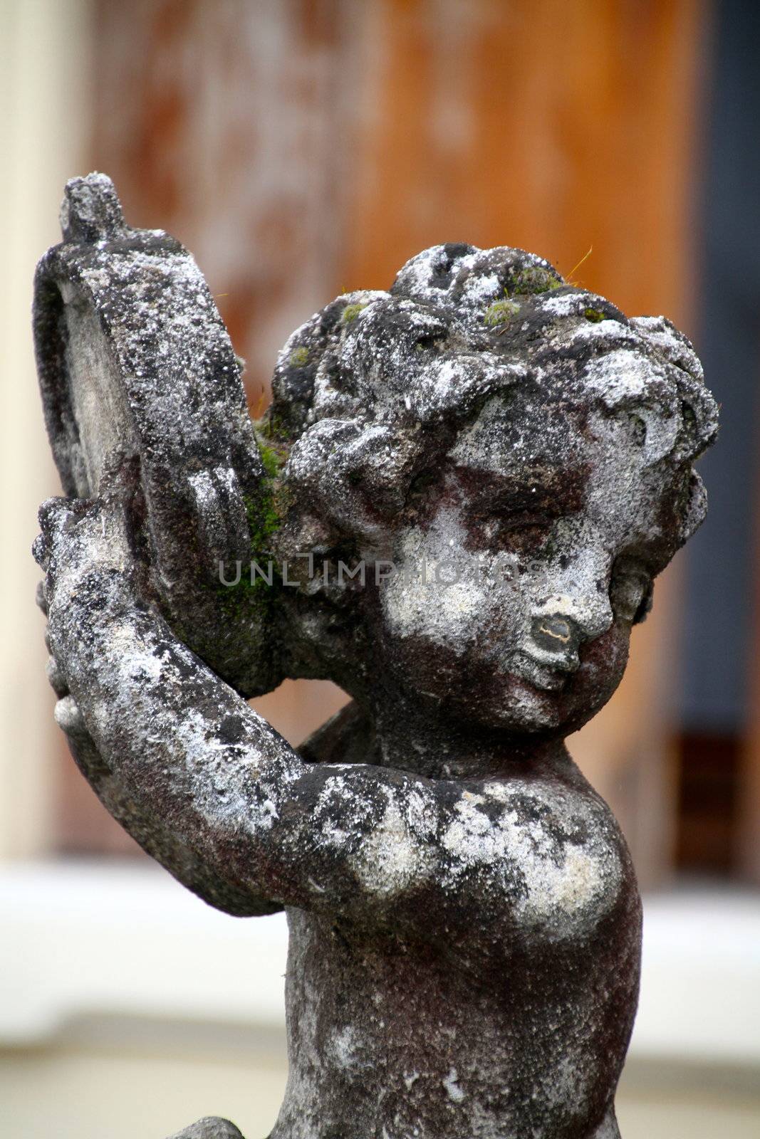 little angel playing the tambourine - old statue