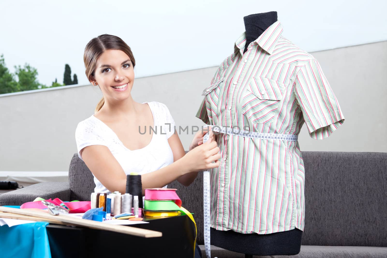 Female fashion designer taking measurement of shirt.