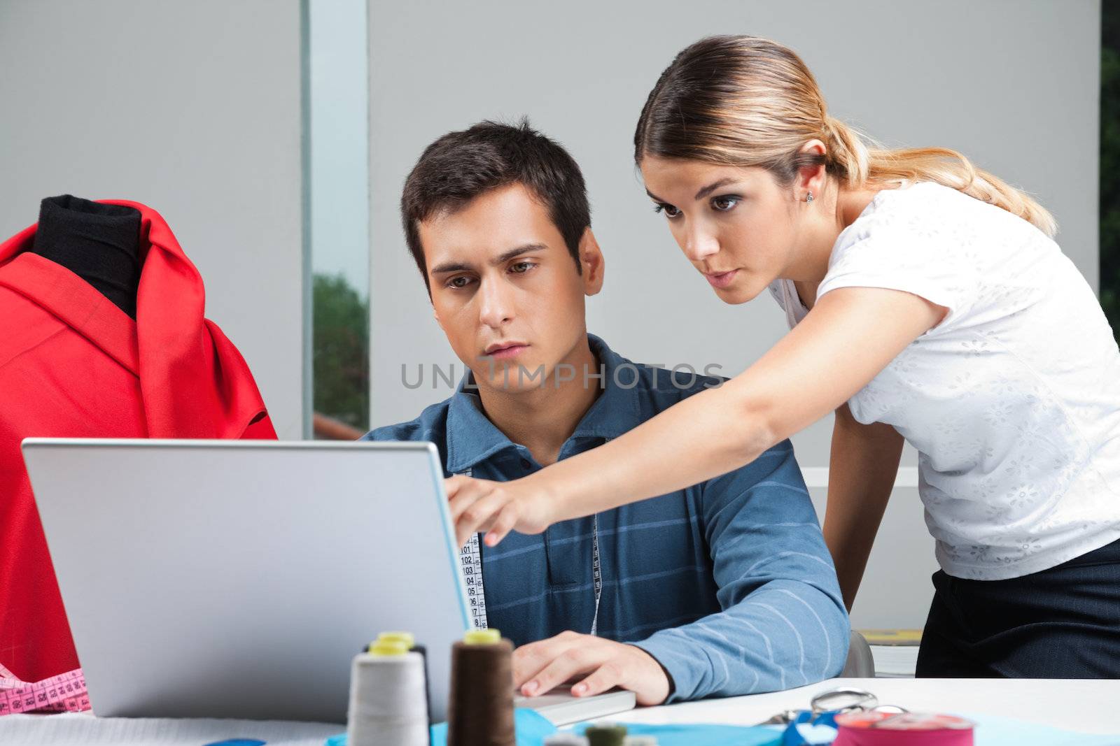 Young male and female fashion designers working on laptop together