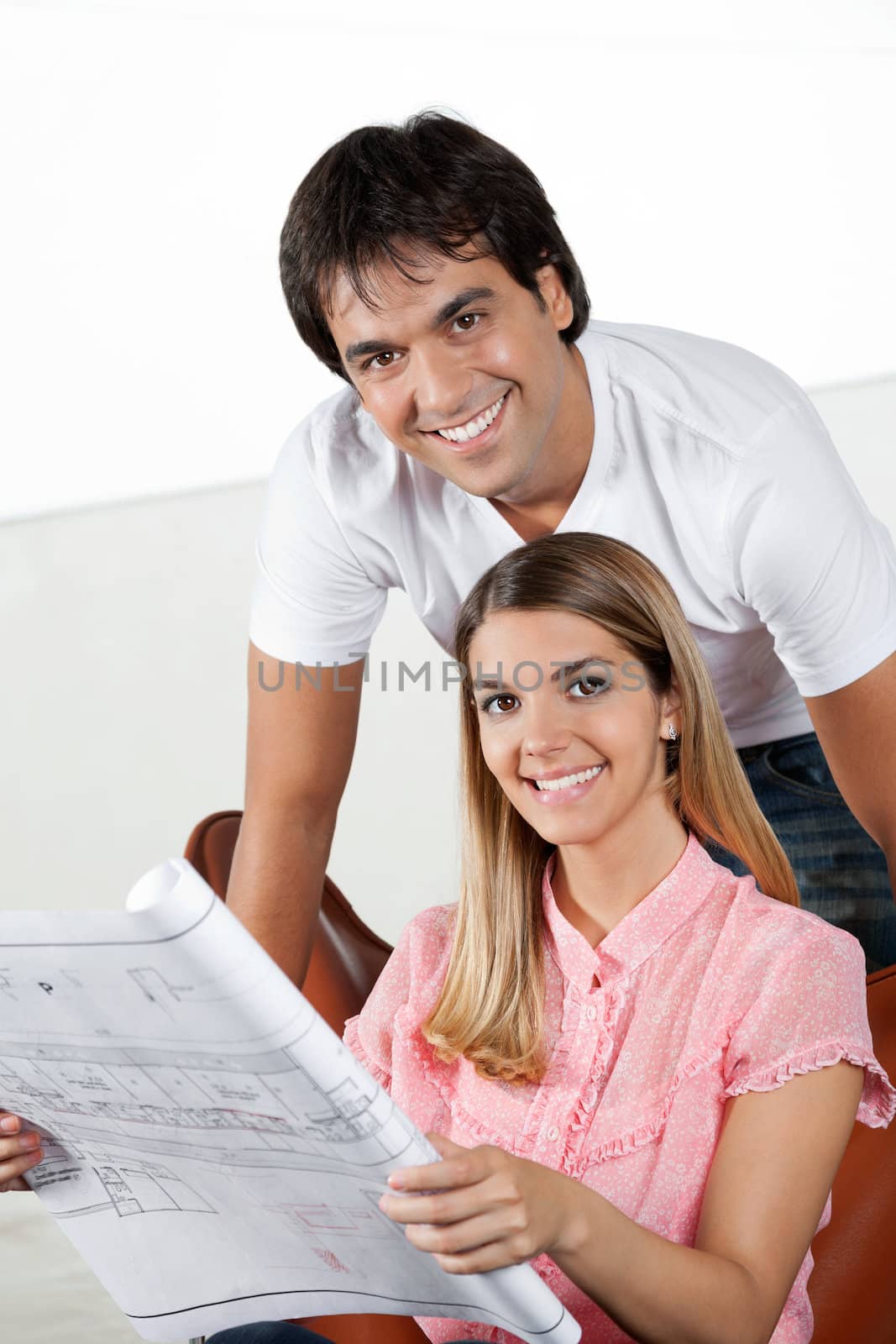 Portrait of young man smiling with woman holding blueprint