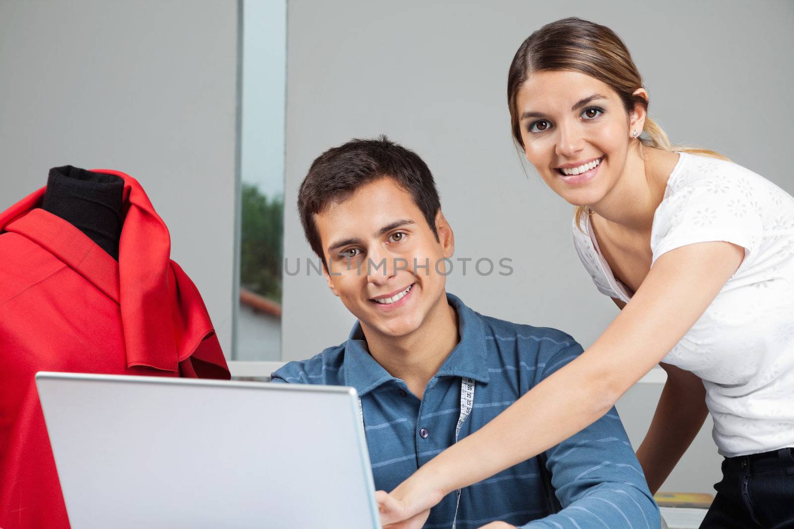 Portrait of young fashion designers working together on laptop